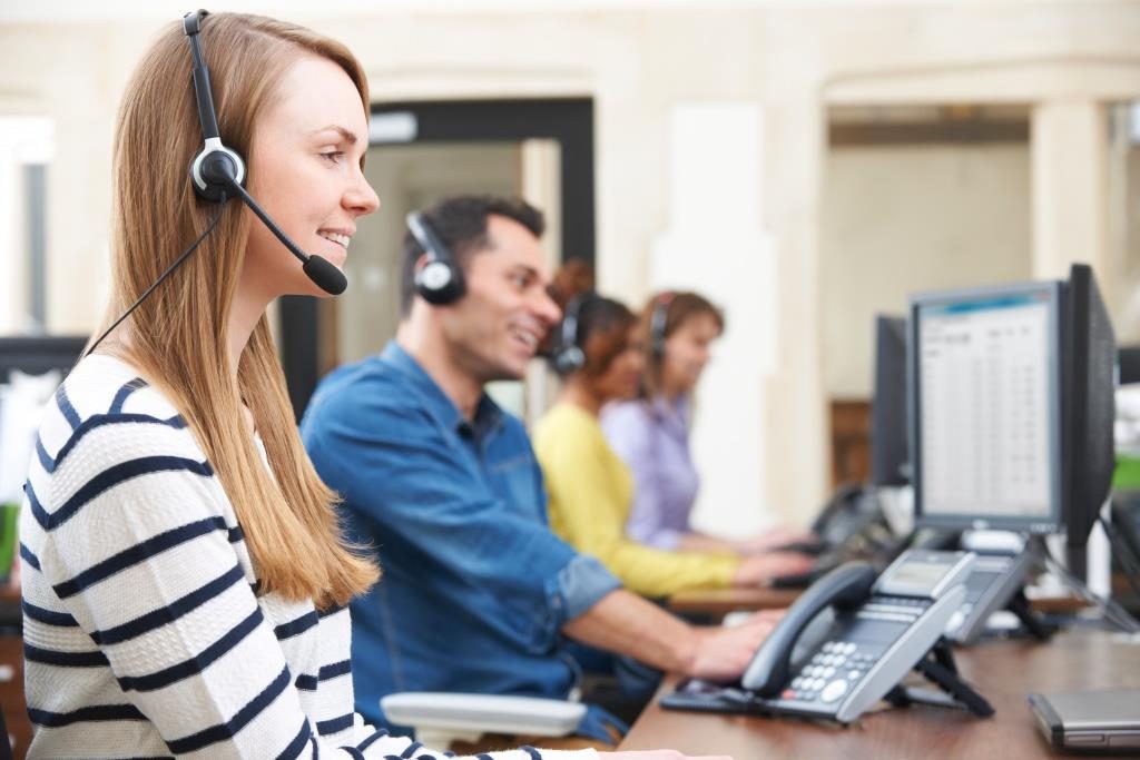 Four people with headsets on in a call center